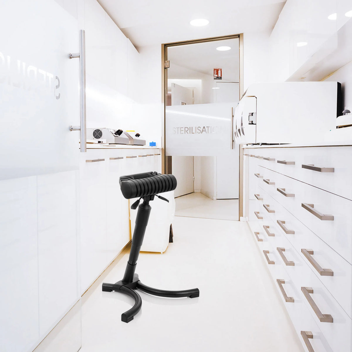 Musta seisomatuki TOP WORK 33 pehmustetulla istuimella ja tähtijaloilla vaaleassa sterilointiympäristössä, valmistaja hjh OFFICE
