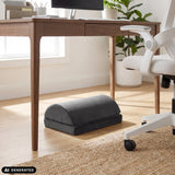 Musta Podi Velvet 1 -jalkatuki työpöydän alla, valmistaja hjh OFFICE (tekoälyllä luotu kuva)