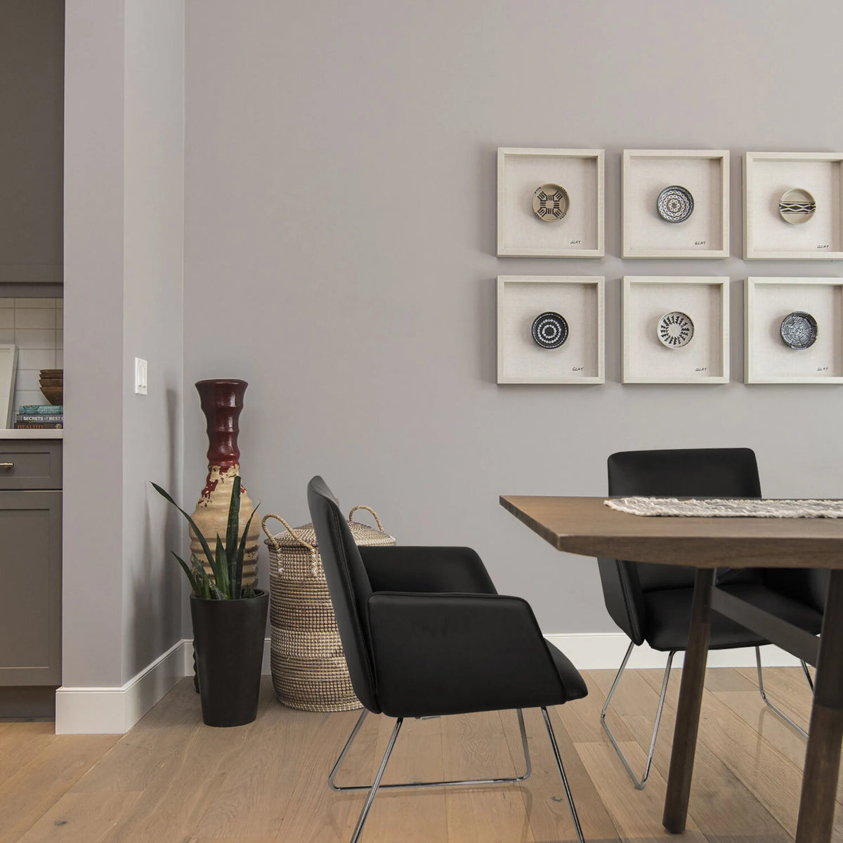 Musta pehmustettu tuoli DESIGNIA V ja hoikat metallijalat puupöydän ääressä, valmistaja hjh OFFICE