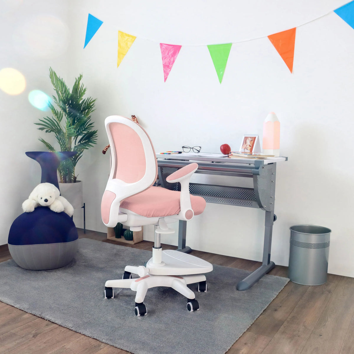 Vaaleanpunainen lasten tuoli KID ERGO valkoisilla käsinojilla ja pyörillä työpöydän ääressä, valmistaja hjh OFFICE